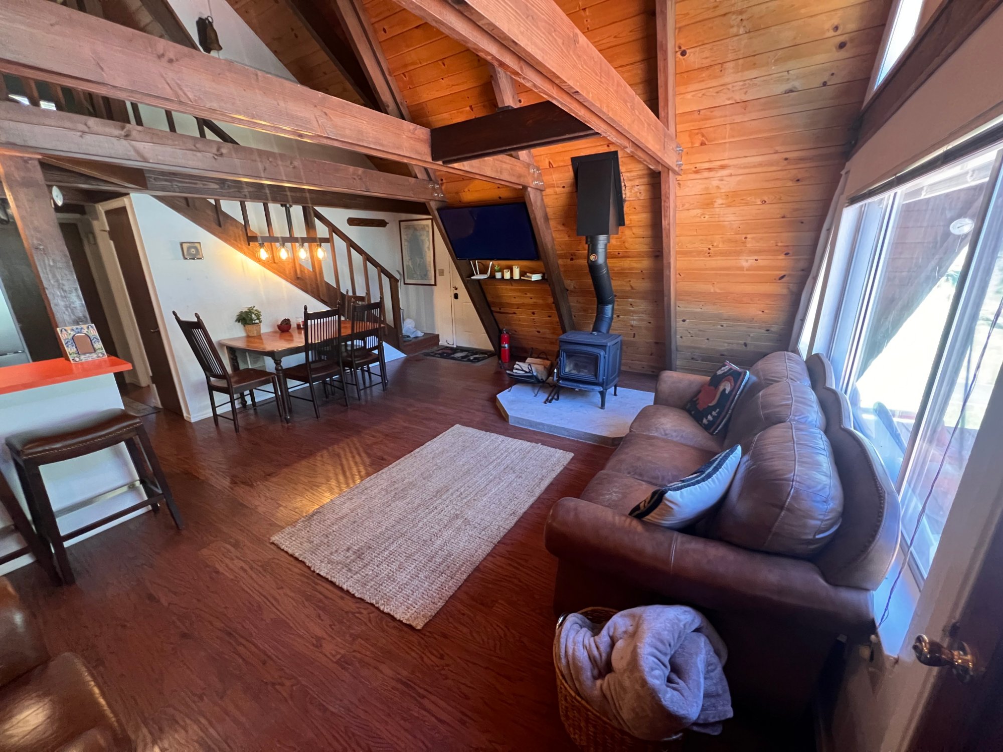 Living room with soaring A-Frame ceilings, leather sofa, and wood stove