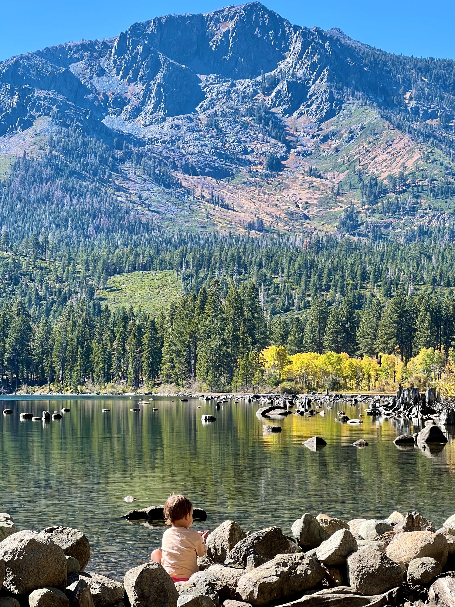 Child sitting on rocks at Fallen Leaf Lake with mountain backdrop
