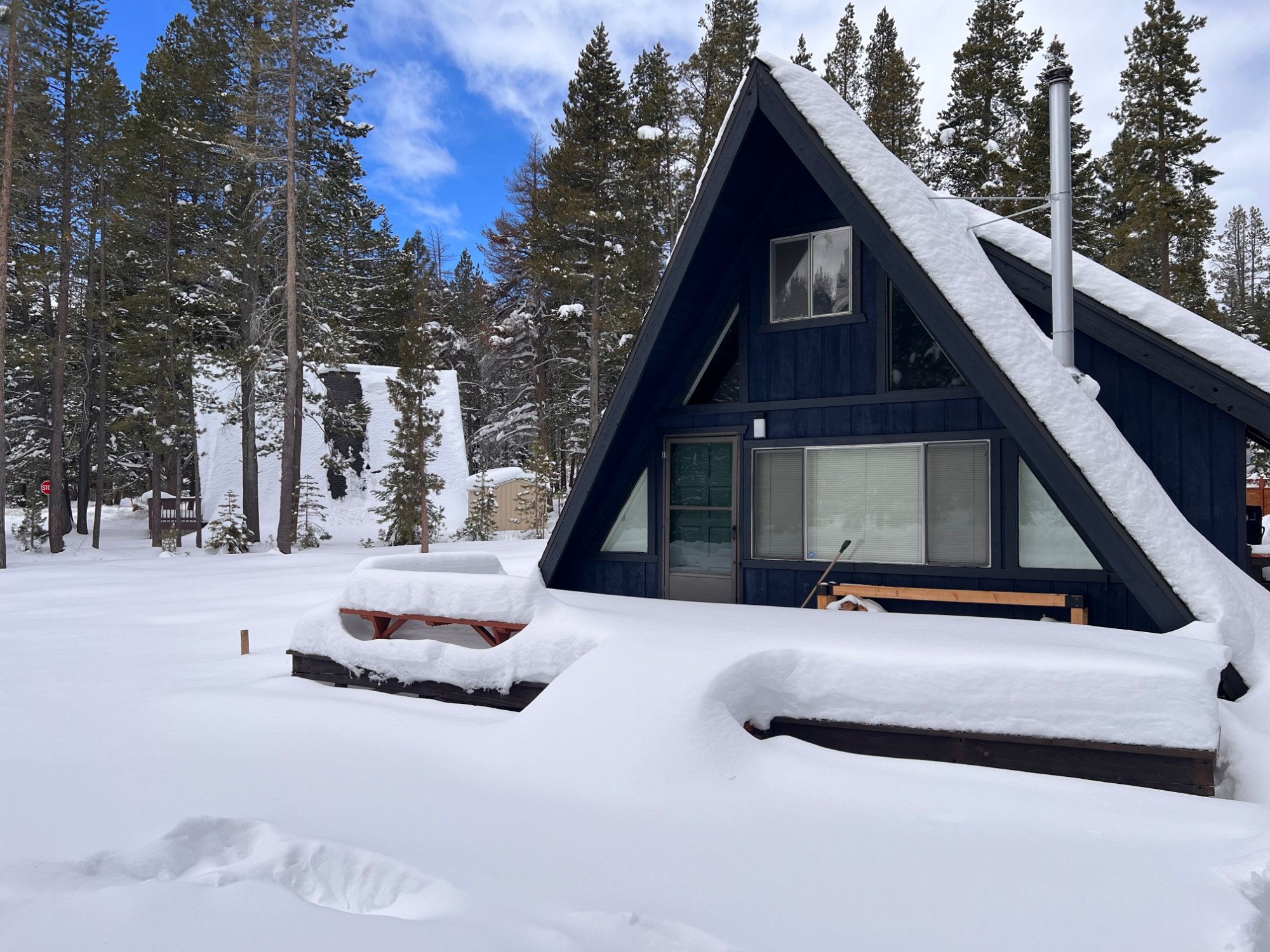 A-Frame cabin blanketed in fresh Sierra snow among tall pines